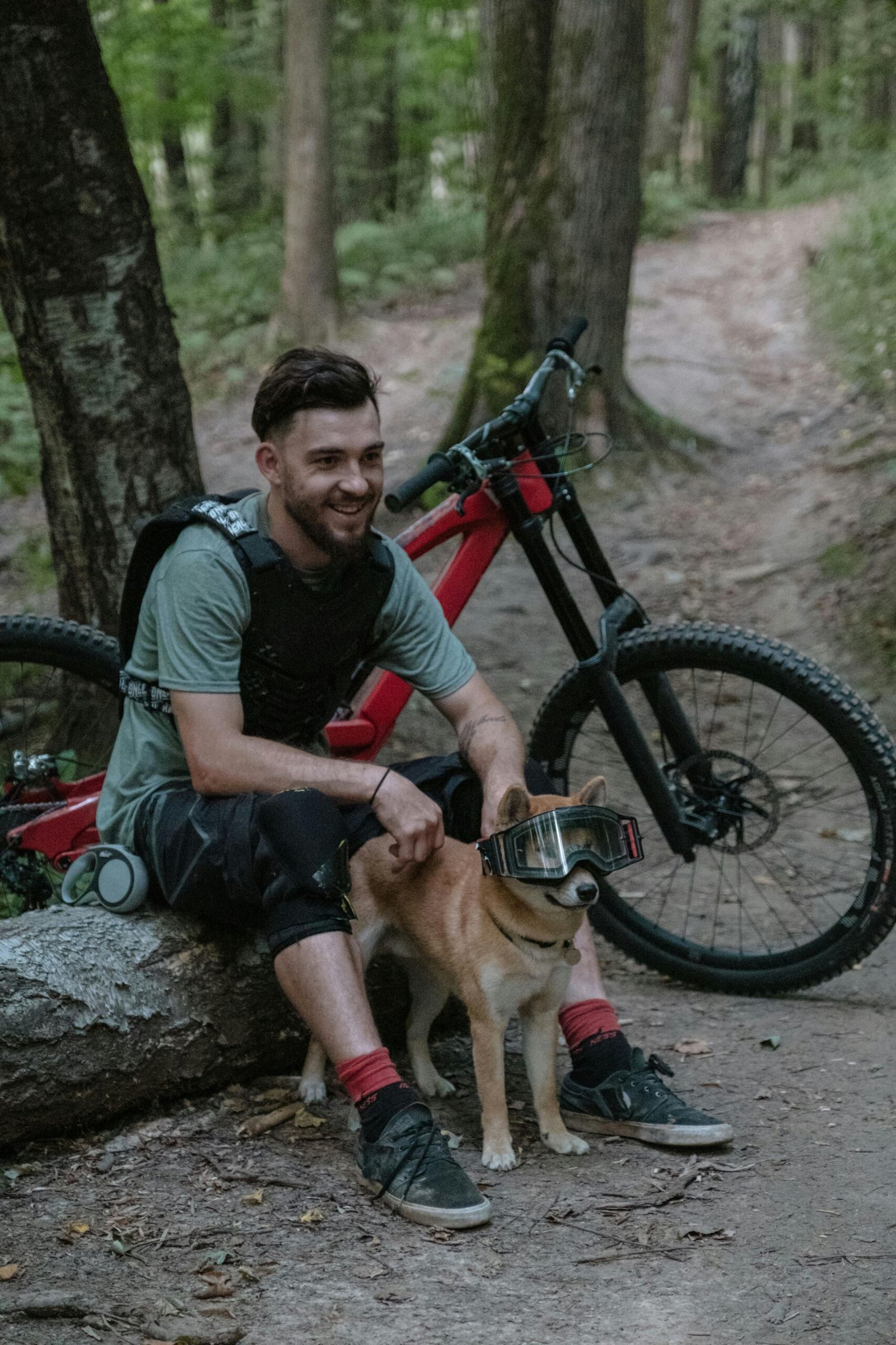 Mountain biker relaxing with his dog on a serene forest trail.